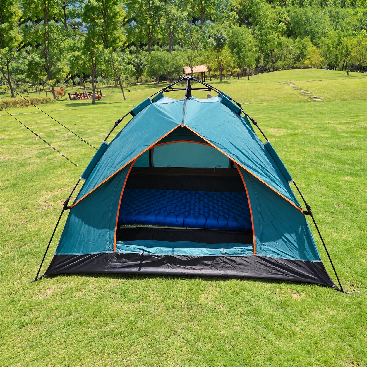 Dome tent on grass with an exposed automatic hub, orange door edging and an open front entrance.