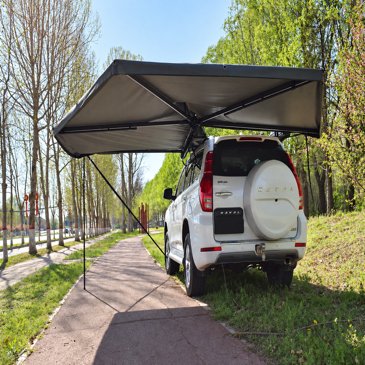 Dark L-shaped awning extending along an SUV side and over its rear with ground support poles