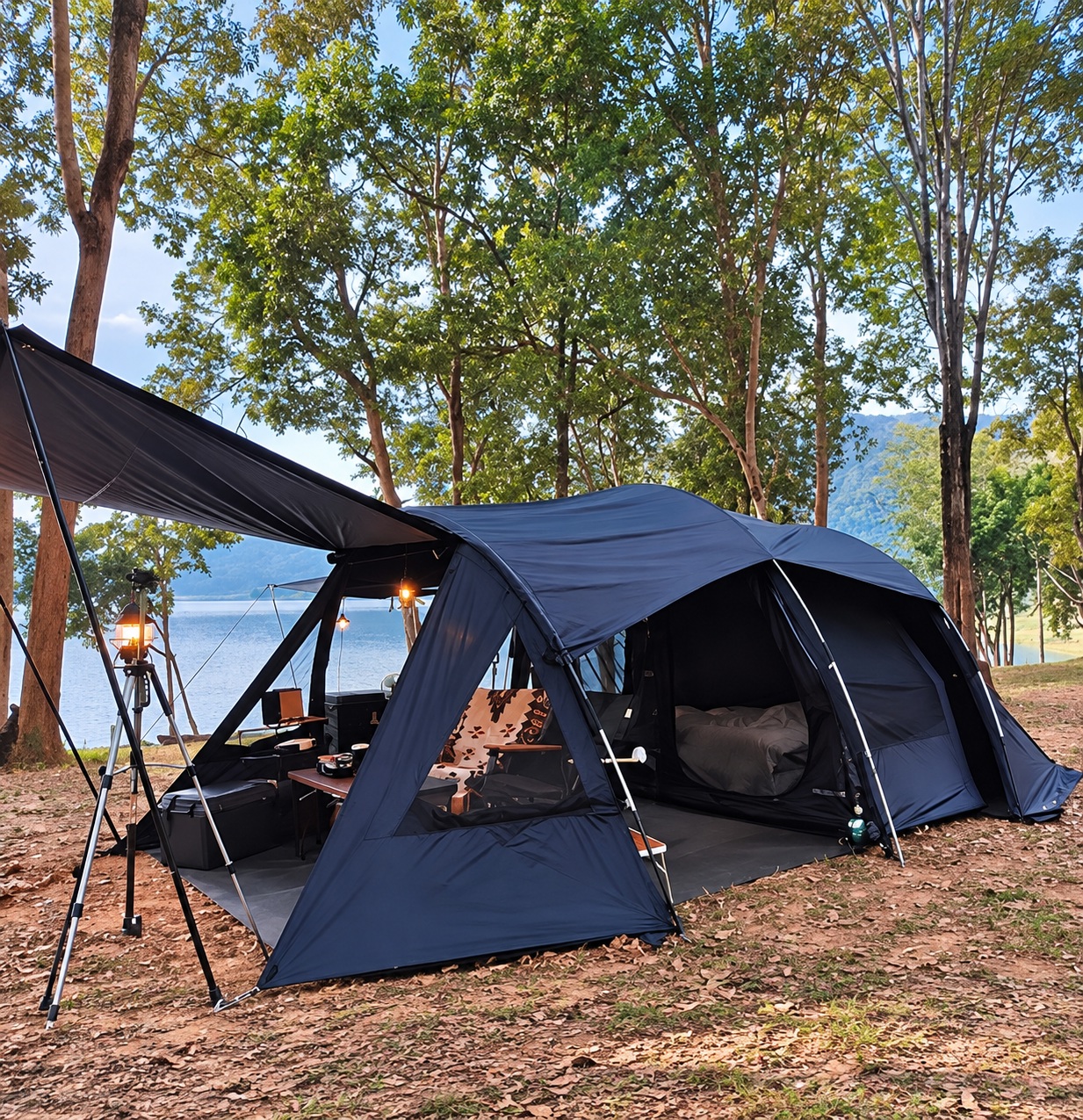 Dark navy tunnel camping tent with an extended awning, open entrances, poles and guy lines in a pine campsite