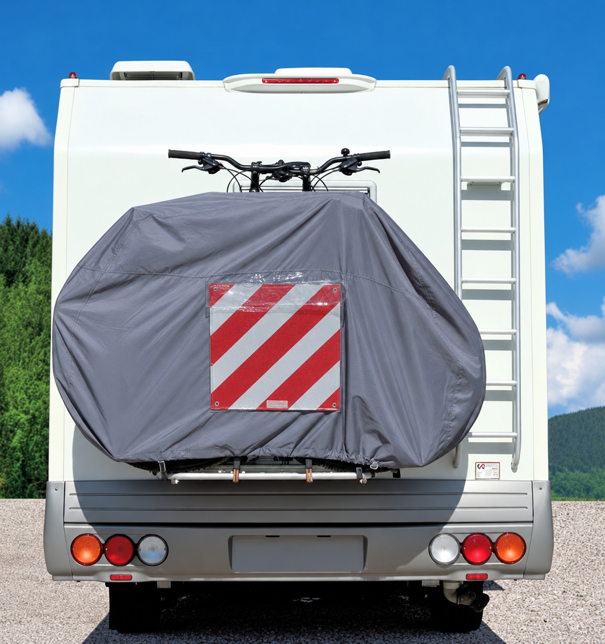 Gray cover over bicycles on a motorhome rear rack, with a striped sign displayed inside a transparent pocket.