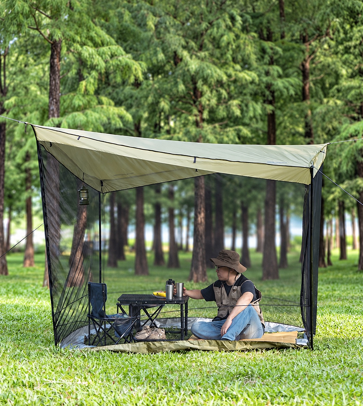 Ridge canopy with dark drop mesh walls around a campsite seating area on grass