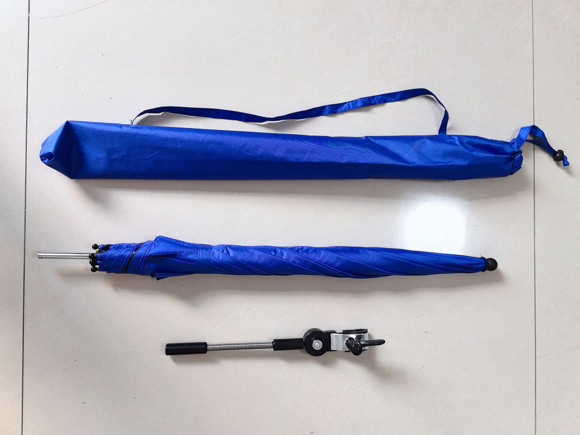 Folded royal-blue umbrella with a matching carry sleeve and a separate adjustable black clamp.