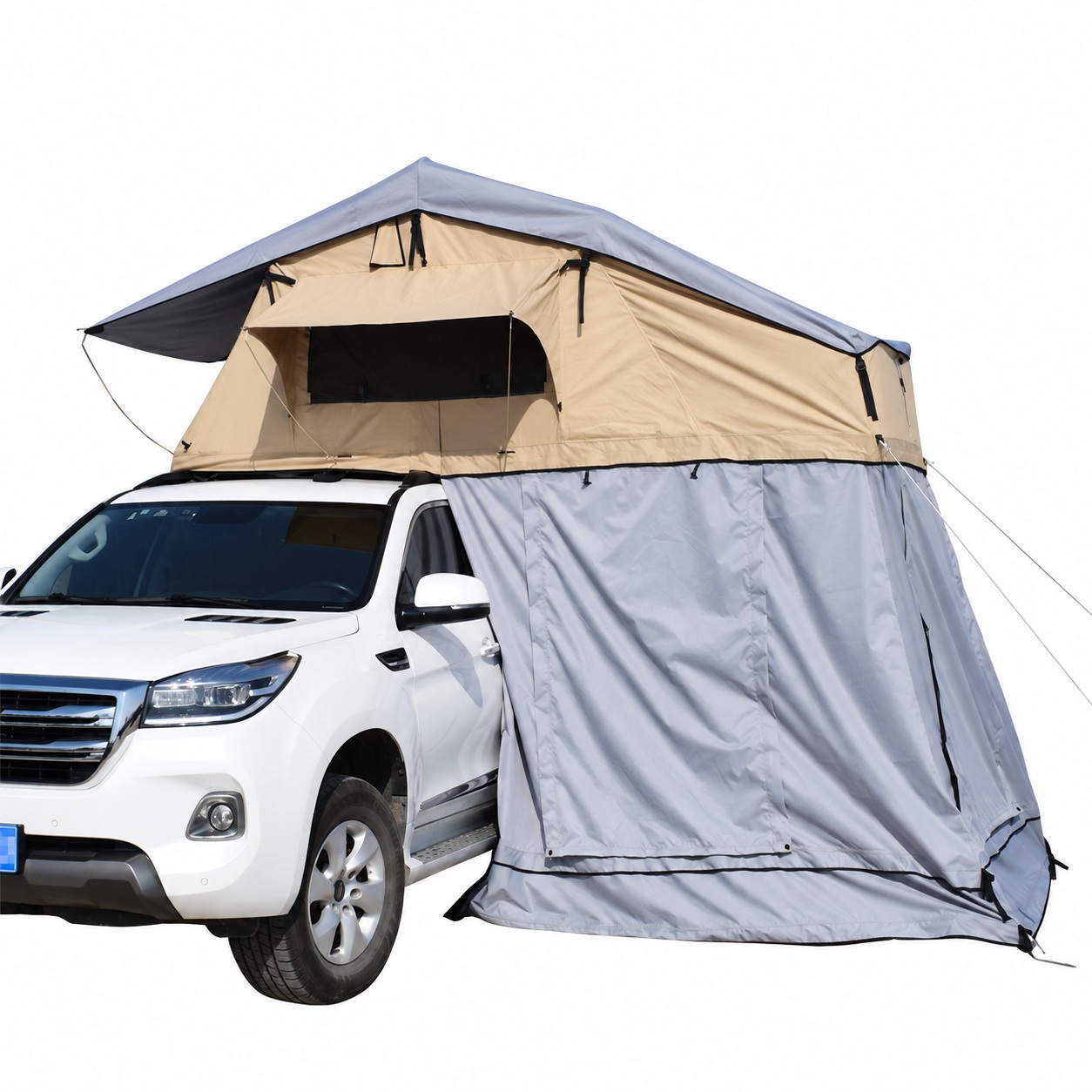 Tan fold-out rooftop tent above a vehicle with a grey fabric annex hanging beneath the entrance overhang.