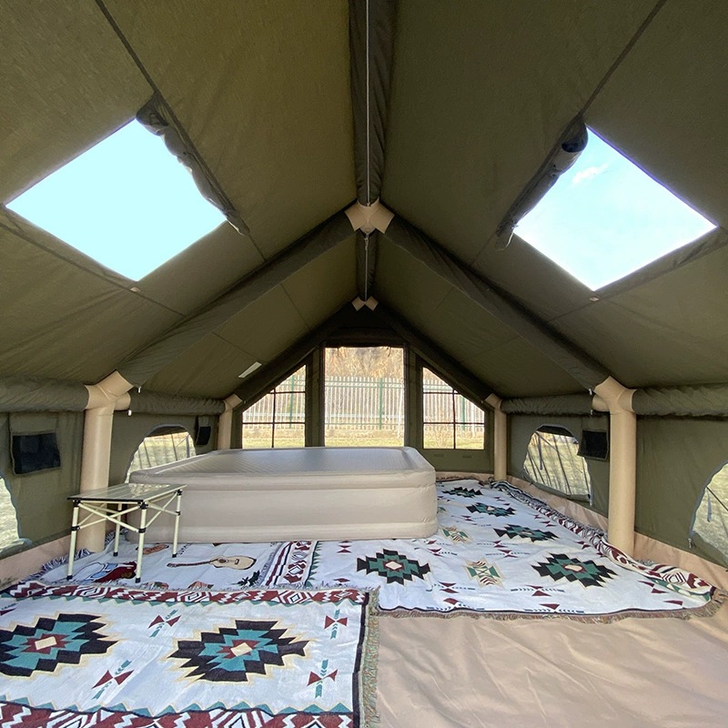 Interior of an olive-green gable cabin with pale air columns, clear roof windows and side windows.