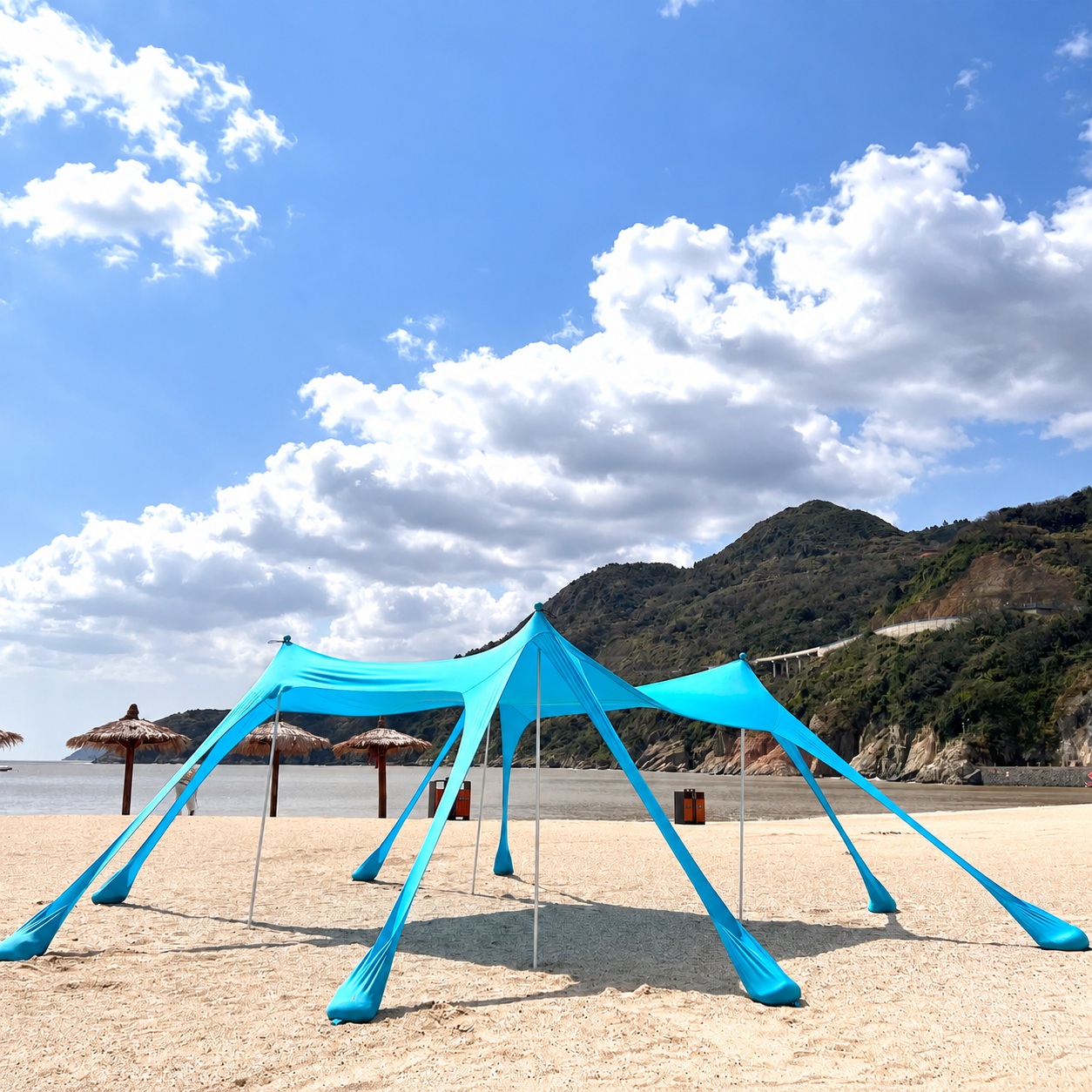 Blue stretch beach canopy with four support poles and eight fabric sand anchors.